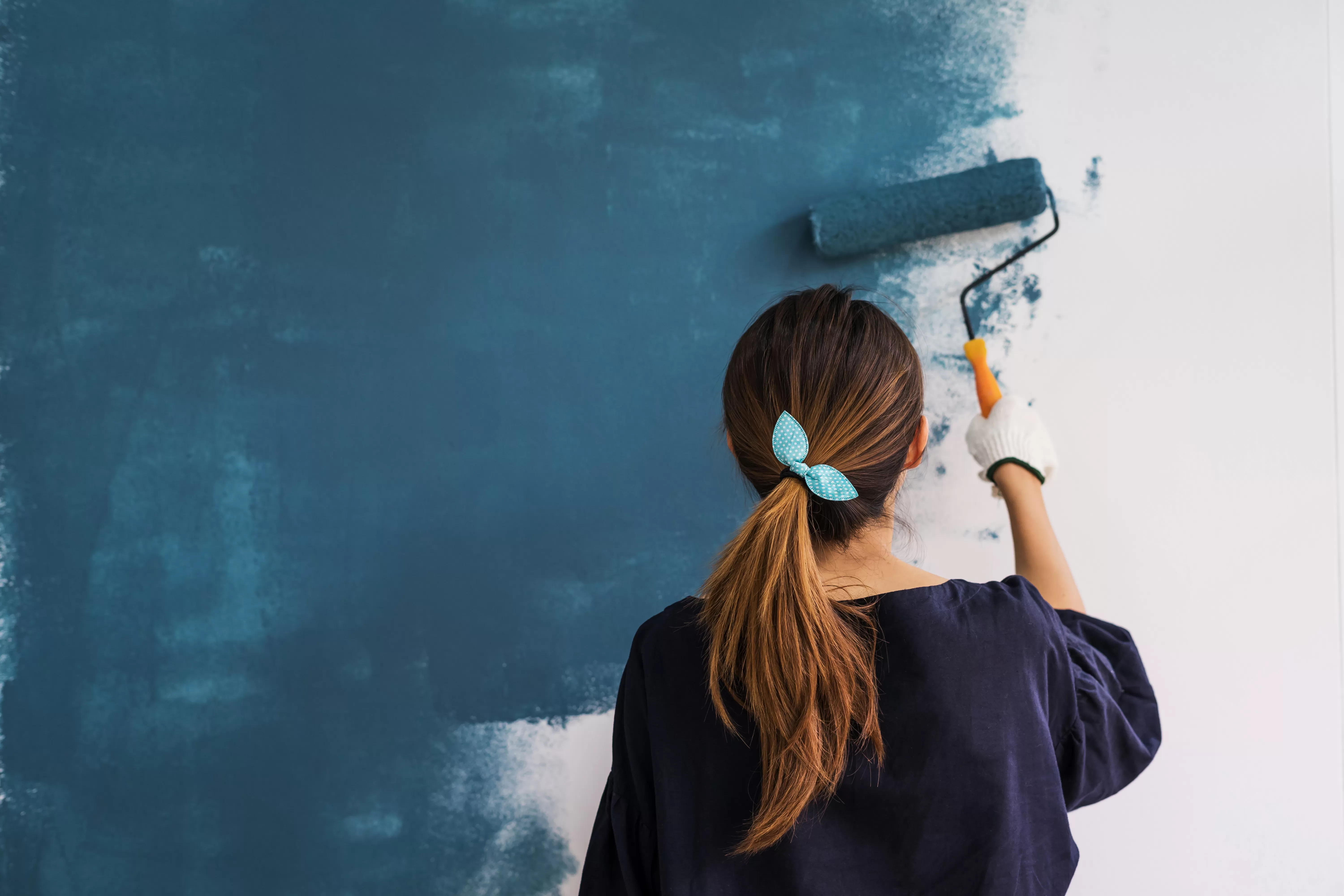 Woman painting her wall blue
