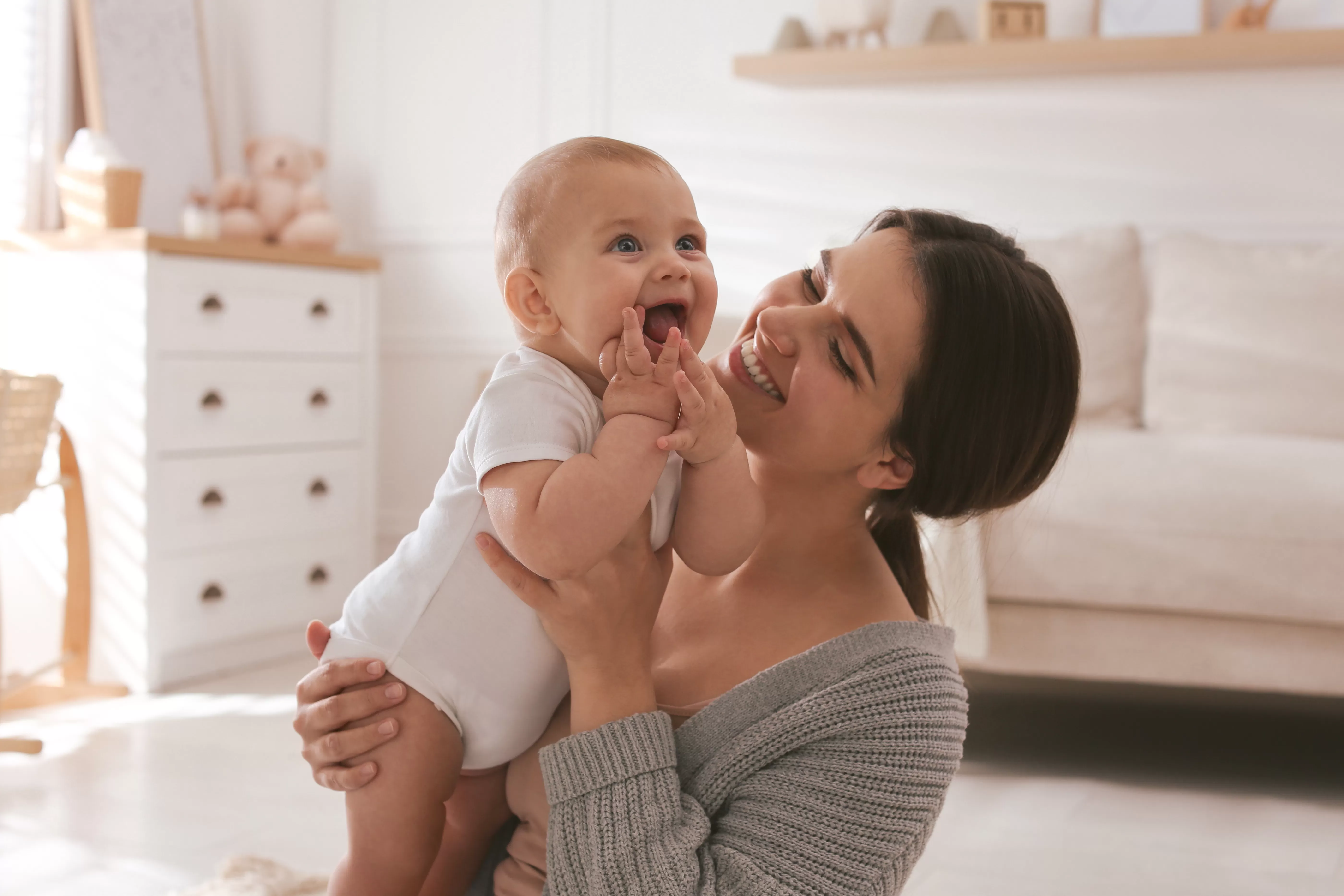 Woman holding a smiling baby in their home