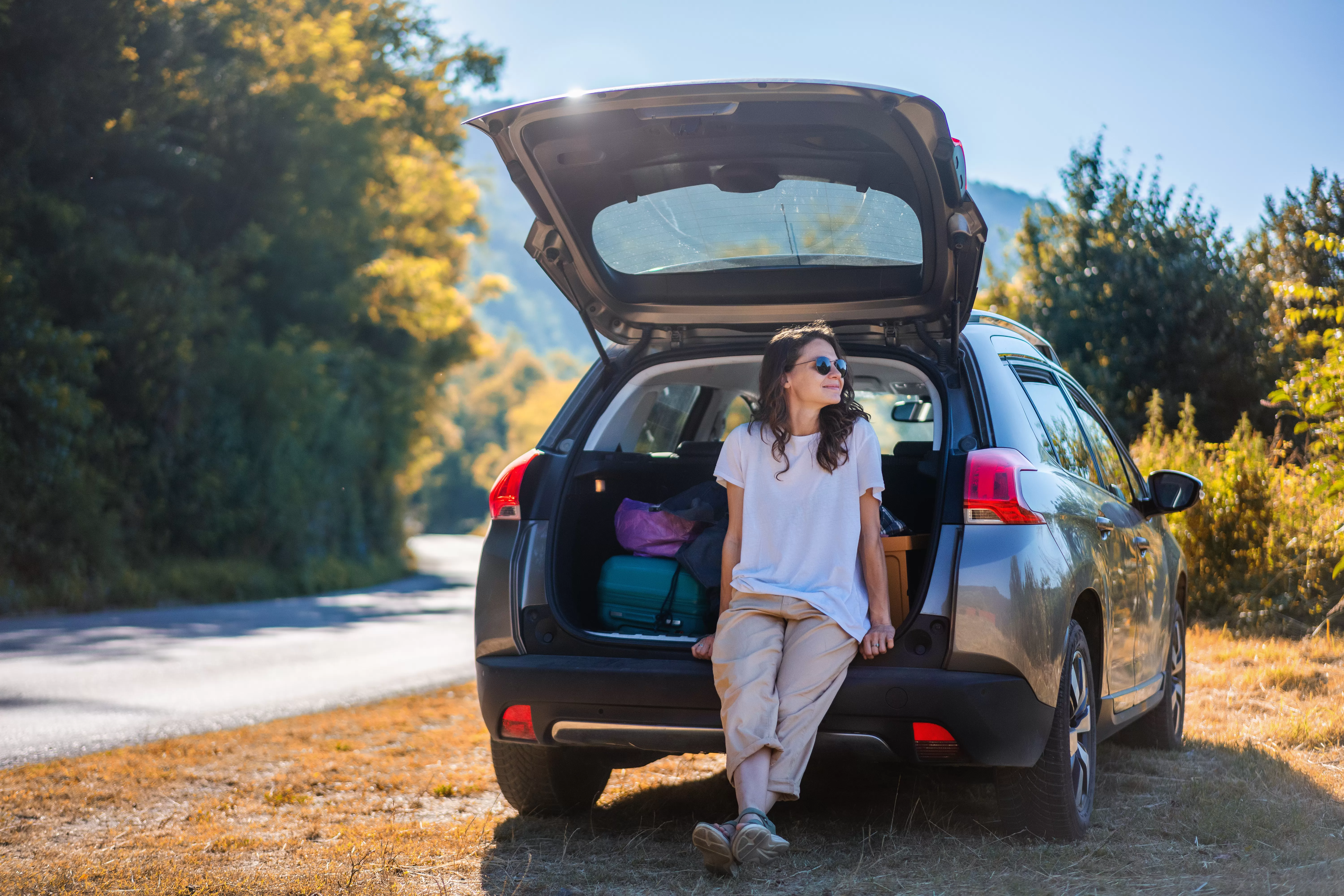 A woman sits on the tailgate of a car she financed with a credit union used auto loan.
