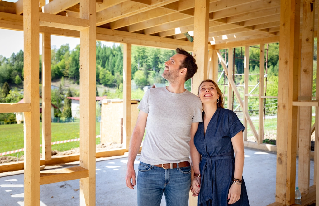 Couple holding hands as they walk through unfinished house